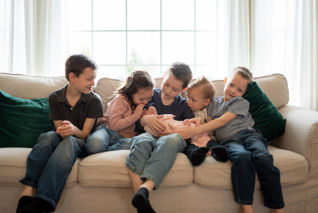 Five siblings snuggled on the couch with their new baby sister for Puyallup newborn photos