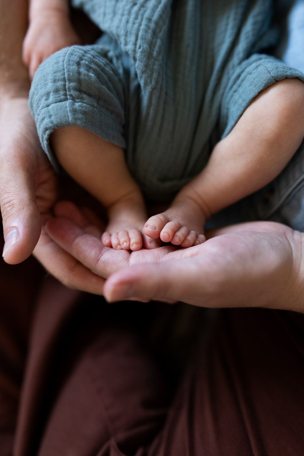 Close up photo of baby's feet resting in the palm of her dad's hand