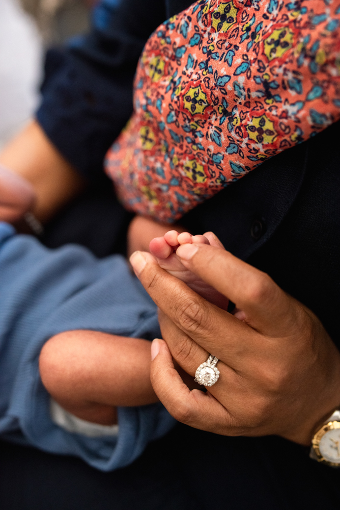 Mother holding her newborn baby's toes during a lifestyle newborn photography pose in natural light