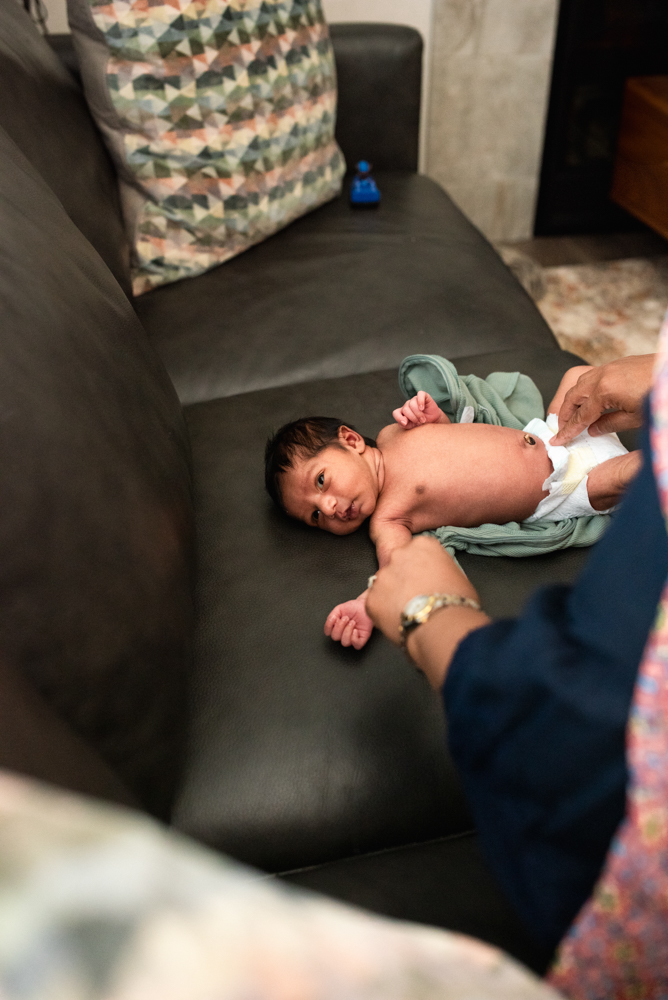 Newborn baby lying on a couch during a relaxed lifestyle newborn photography pose at home