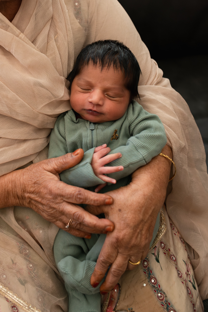 Newborn baby sleeping in a family member’s arms during an in-home lifestyle newborn photography pose.