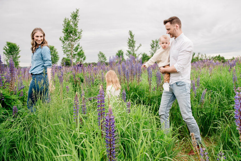 Family walking through lupine field in Puyallup WA at Van Lierop Park for lifestyle family photos