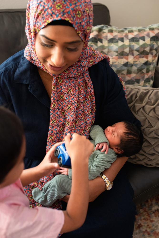Toddler holding toy car during relaxed and authentic newborn family photo session at home