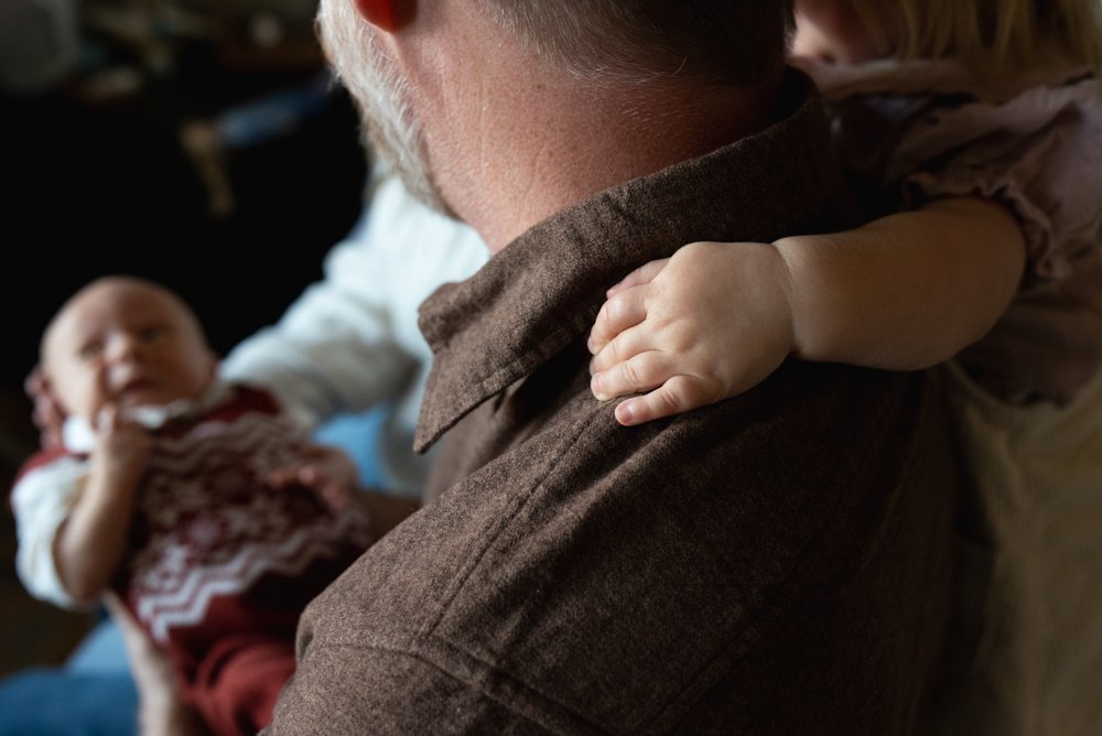 Lifestyle detail shot of a toddler’s hand holding their parent’s neck during in-home family photos